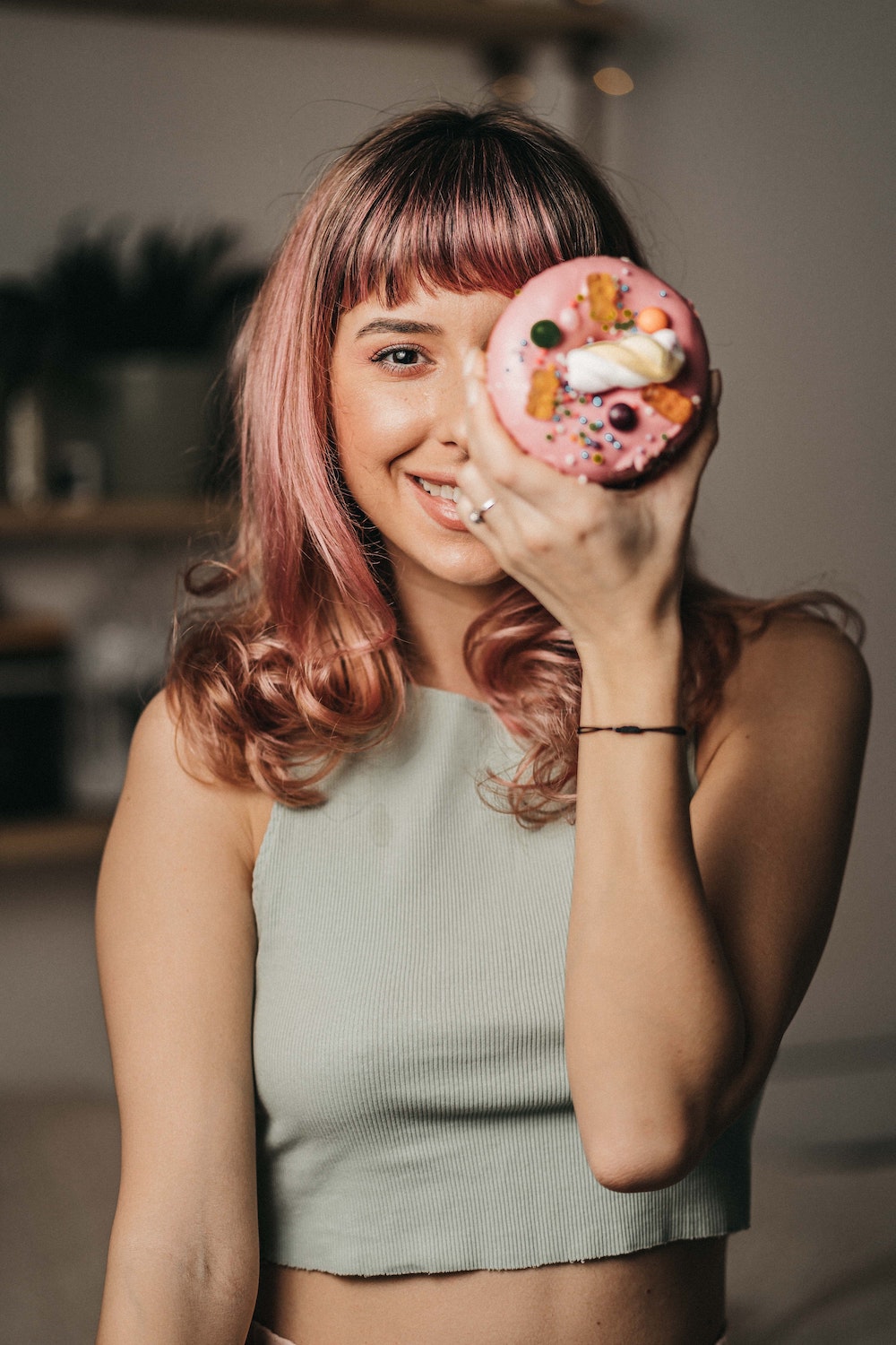 Glückliche junge Frau mit einem rosafarbenen Donut